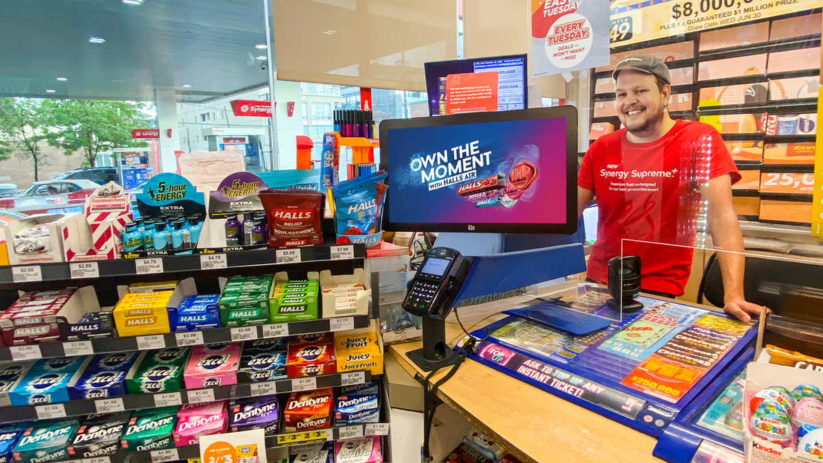 Local convenience store owner smiling behind the counter